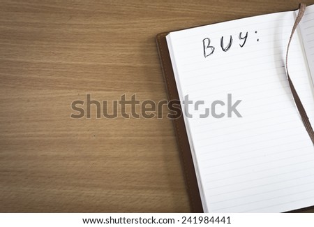 Open note book with BUY list on wood table