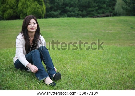 young woman sits down on a lawn