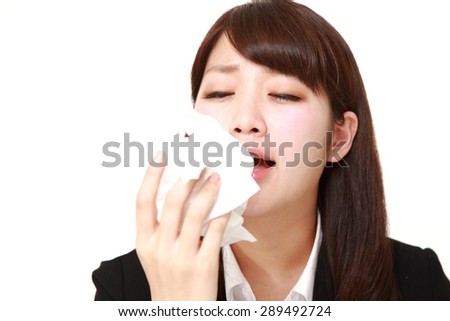businesswoman with an allergy sneezing into tissue