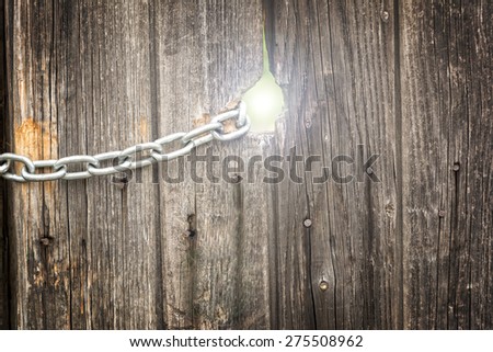 A hole in a vintage wooden picket fence with chain attached and light coming from the hole. Concept for freedom, victory or success
