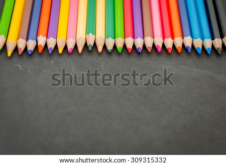 Colorful pencil crayons on a blackboard background