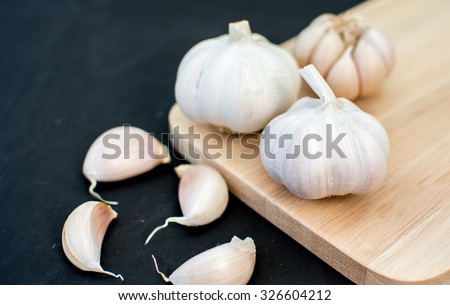 garlic clove, garlic bulb place on chopping block on black background