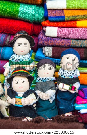 OTAVALO, AUGUST 4, 2012: Traditional dolls in national clothes sitting on a pile of textiles, as usual on weekdays on the most famous markets in South America, on August 4, 2012 in Otavalo, Ecuador