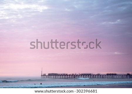 Sunset on the Pacific Ocean, the sun breaks through the mist and famous pier at Pimentel. Peru, Latin America