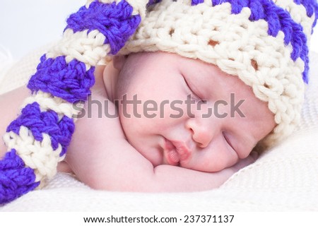 Sweet tiny newborn baby boy in knitted hat is sleeping