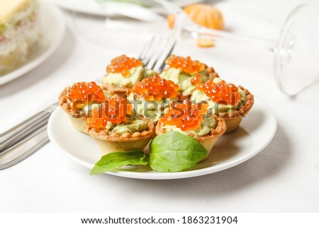 Mini Tartlet With Avocado Cream Decorated Red Salmon Caviar On White Plate With Basil Leaf On The Table. Side View. Stock fotó © 