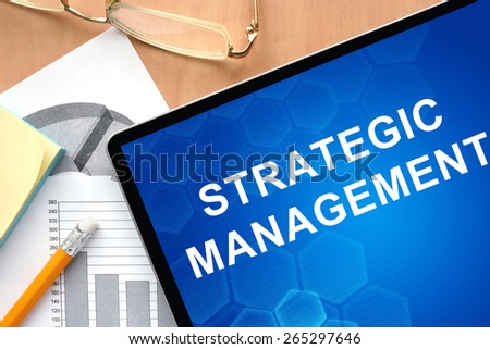 Tablet with words strategic management. Business and management concept.