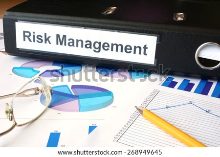 Graphs and file folder with label Risk Management. Business concept.