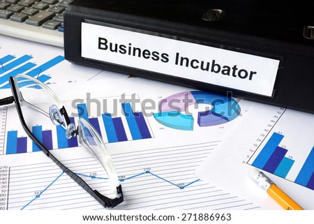 File folder with words Business Incubator and financial graphs. Business concept