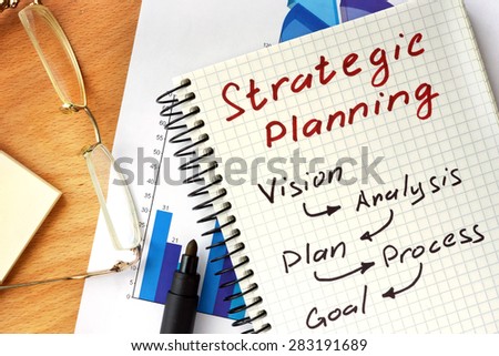 Notepad with  Strategic planning concept on a wooden board.