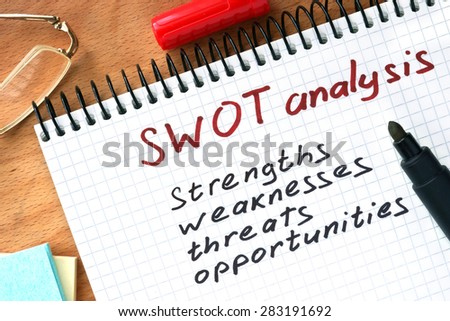 Notepad with  SWOT analysis concept on a wooden board.