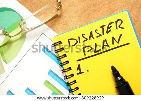 Notepad with disaster plan on a wooden table.