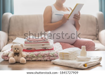 Pregnant woman is getting ready for the maternity hospital, packing baby stuff. pregnant woman preparing and planning baby clothes.  List of things in the hospital.  
