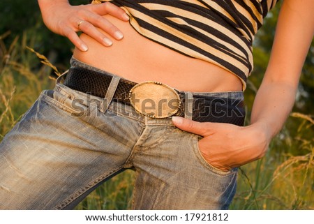 Closeup sexy woman tan belly in jeans with belt over green background