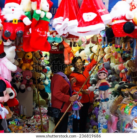 Hanoi, Vietnam - Dec 7, 2014: Christmas decoration store owner helps customer to choose Xmas gift in a store on Hang Ma street