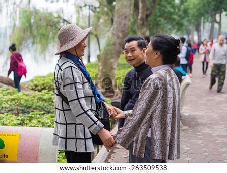 Hanoi, Vietnam - Mar 15, 2015: A couple happily seeing their friend at Hoan Kiem lake, Hoan Kiem district. The women holding hands of each other