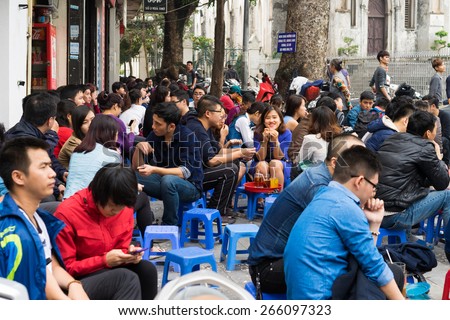 Hanoi, Vietnam - Mar 15, 2015: People drink coffee, tea or juice fruit on cafe stall on sidewalk in Nha Tho street, center of Hanoi. Drinking on street is a typical culture of Hanoi