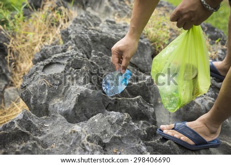 Man hands picking up litters on rock at tourism place