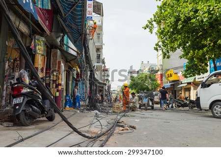 Hanoi, Vietnam - June 14, 2015: Workers fix damaged telecommunication cables after super heavy wind storm in Truong Dinh street. This is the heaviest wind storm for years in Hanoi