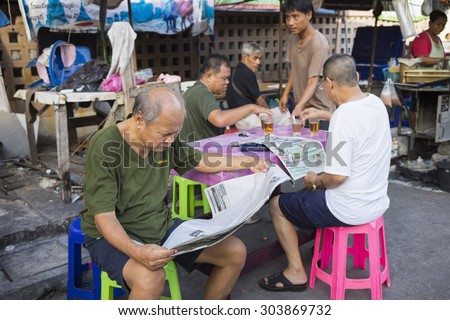 Bangkok, Thailand - June 28, 2015: Old men reading newspaper at a tea stall on Bangkok street