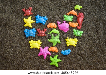 Plastic sea animals on man made sand. Children toys. Heart shape