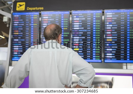 Male passenger at the airport, looking at the flight information board
