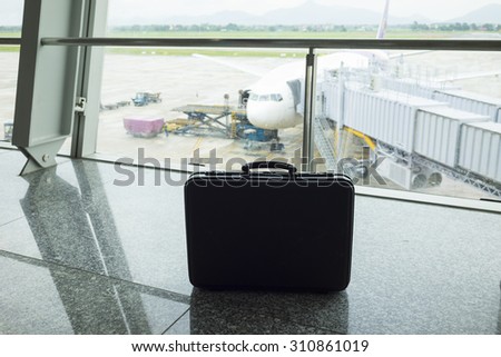 Business man suitcase against air plane on background at airport. Concept of business man travelling by airway