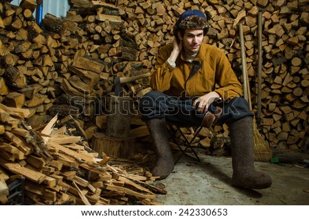 Young russian woodcutter in village. Fire wood background