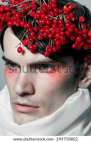Unusual portrait of young man with neck covered with a white cloth. On his head a crown of Viburnum.