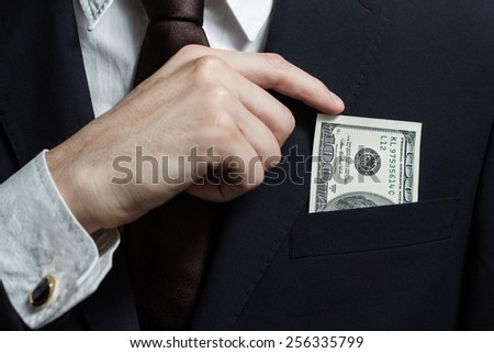 Close up of money in male suit pocket. Puts money in your pocket
