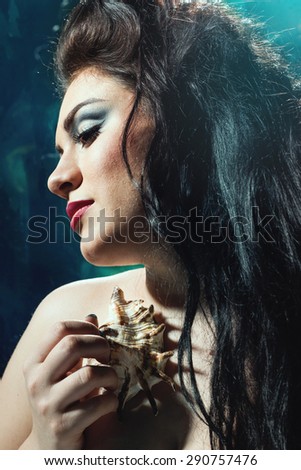 Head shot of young beautiful,woman with shell in arms.