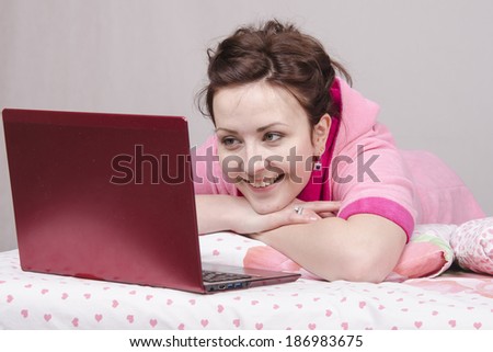 The girl lying in bed and works in the laptop