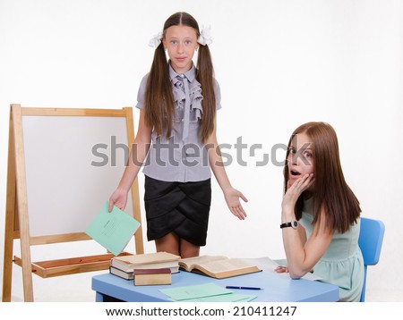 Pupil stands at the blackboard, the teacher sits at  desk and listens to the student