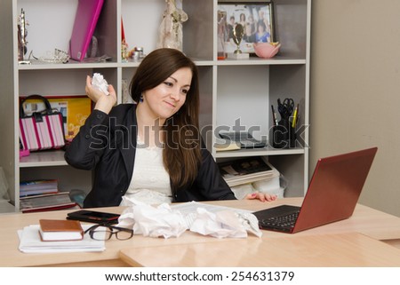 The girl is going to throw crumpled piece of paper into a computer screen