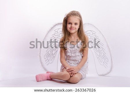 Six year old girl in a bright angel costume with wings on a white background