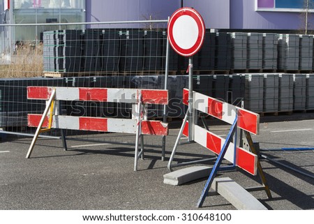 Road closed sign and a red and white striped construction barrier because of road construction.