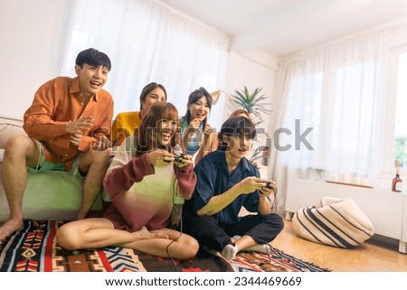 Similar – Image, Stock Photo Friends playing video game at home. Gamers playing online in dark room lit by neon lights. Competition and having fun