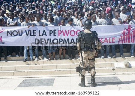 CAP-HAITIEN, HAITI - NOV 18,  Anti-Riot Soldier stands in front of crowd asking for peace and development while waiting for the president Martelli visit on November 18, 2013 in Cap-Haitien, Haiti