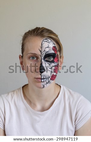 Scary young blond girl with face painting skull with roses