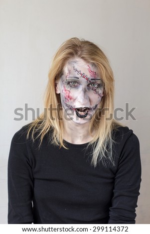 Attractive young blond girl with halloween zombie face painting