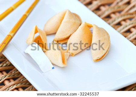Chinese Fortune Cookie with blank paper on white dish with chop sticks. Shallow DOF