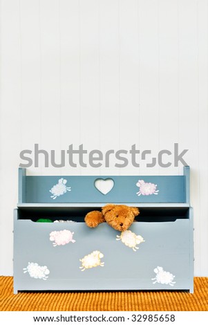 Teddy bear poking his head out of a child\'s toy box.