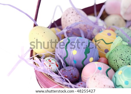 Basket of Easter eggs isolated on white. Shallow DOF with selective focus on the large purple egg in center.