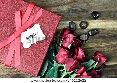 Gift box with long stem red roses and chocolates over an old wooden background with room for copy space.
