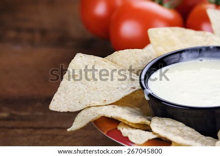 Queso Blanco or White Cheese Sauce with corn tortilla chips and fresh tomatoes. Extreme shallow depth of field with selective focus on cheese dip.