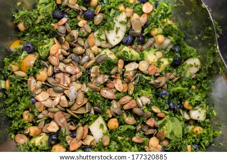 Kale salad with pear, pumpkin seed, blueberry in silver salad bowl full frame