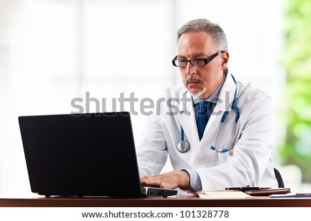 Portrait of a mature doctor using his laptop computer