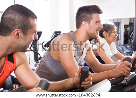 Happy people doing indoor biking in a fitness club