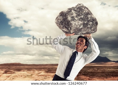 Stressed businessman trying to lift a rock