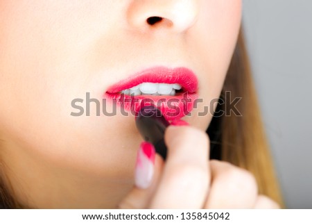 Gorgeous woman applying lipstick